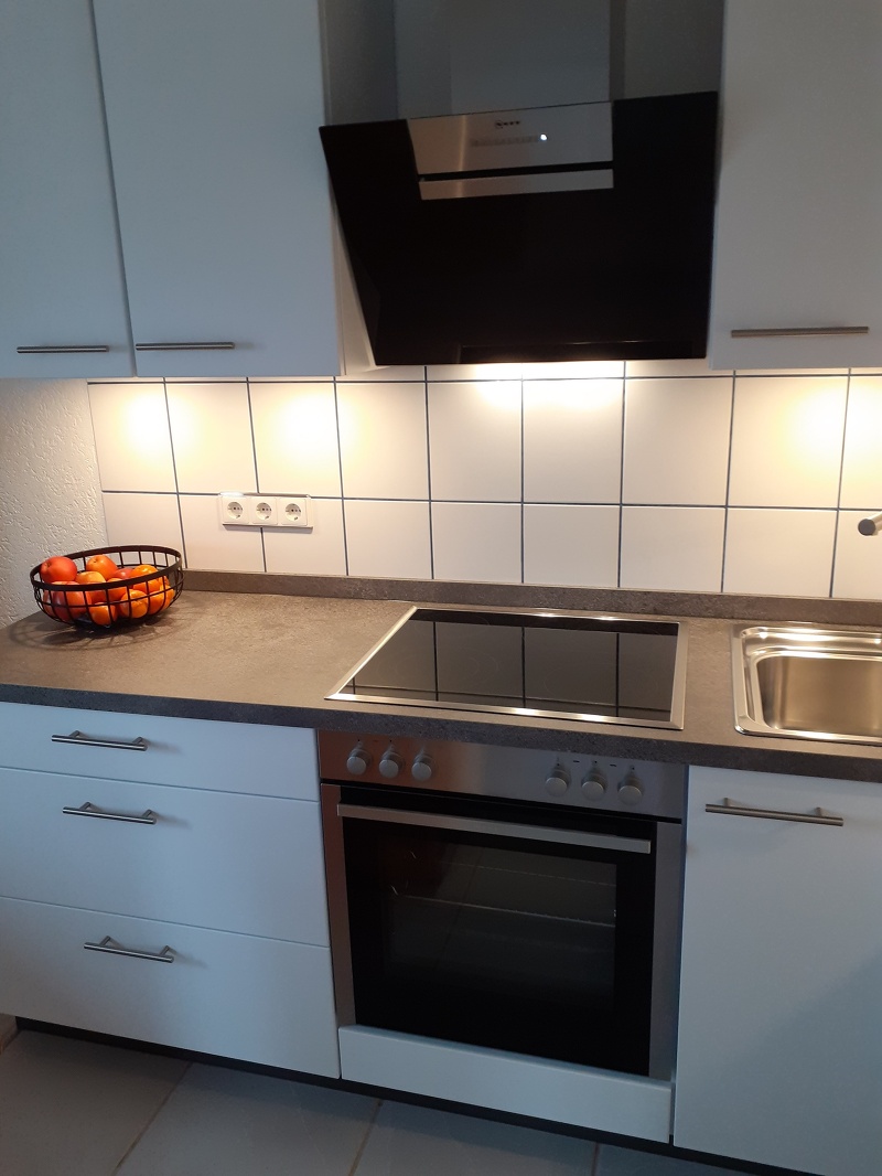 Ausschnitt einer Küche mit dem Blick auf den Herd und Schränke links und rechts