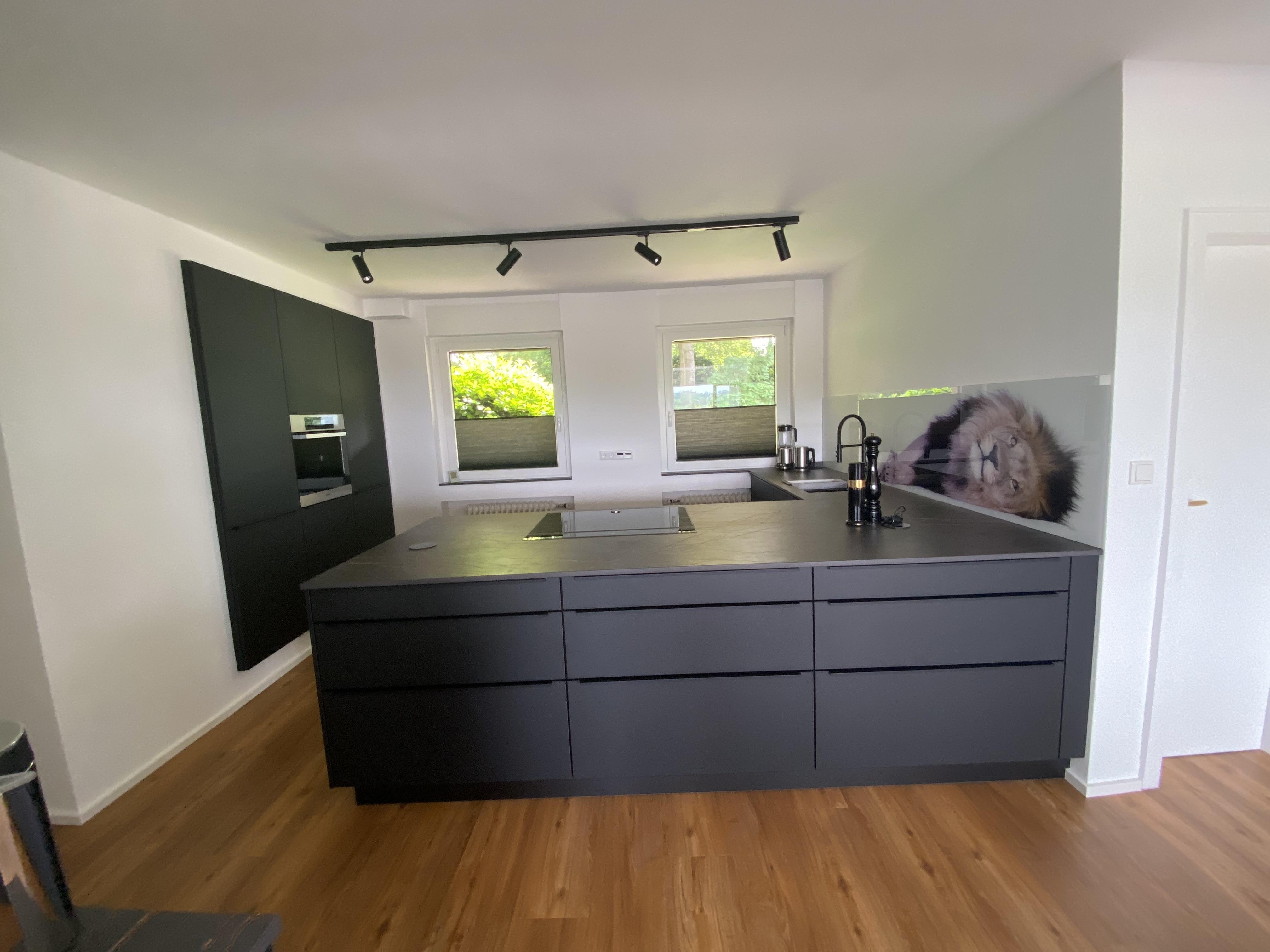 Schwarze Küche mit einer Kücheninsel und eingekofferten Hochschränken