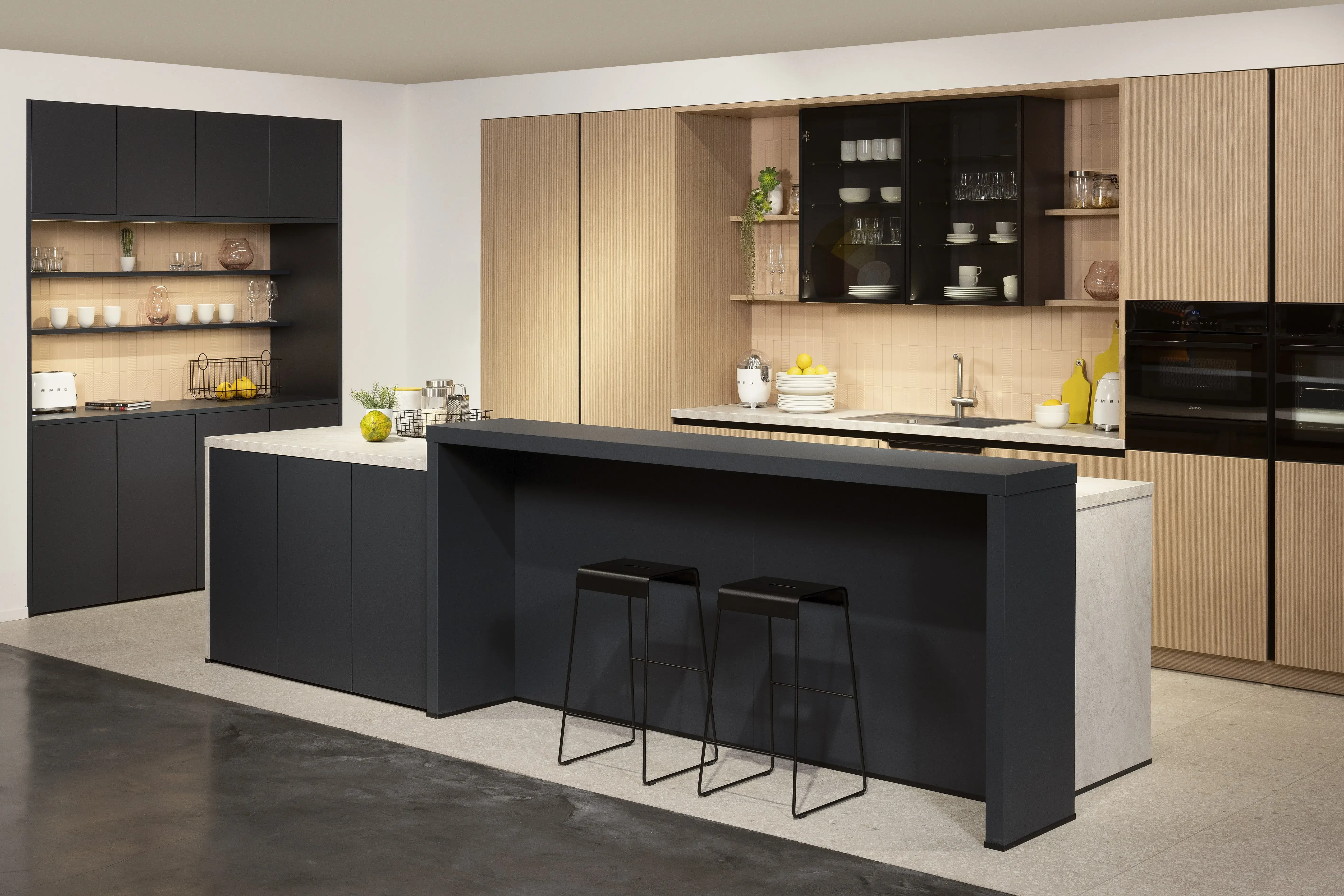 APL: Sandstein beige NB Front: Rillenoptik Eiche natur NB Front: MAC Tiefblau matt Korpus: Lavaschwarz Griff: Metallgriff Schwarz Geräte: Juno, Muldenlüfter BORA Armatur: Franke Spüle: Franke   Features: Kücheninsel mit Theke, Fliesen in Nischenrückwand, eingekoffertes Sideboard, Lichtstimmungen, offene Regale, Handtuchhalter Clip für Unterschranktüren, Kompaktbackofen, Planung ohne Sockel bodentief. 