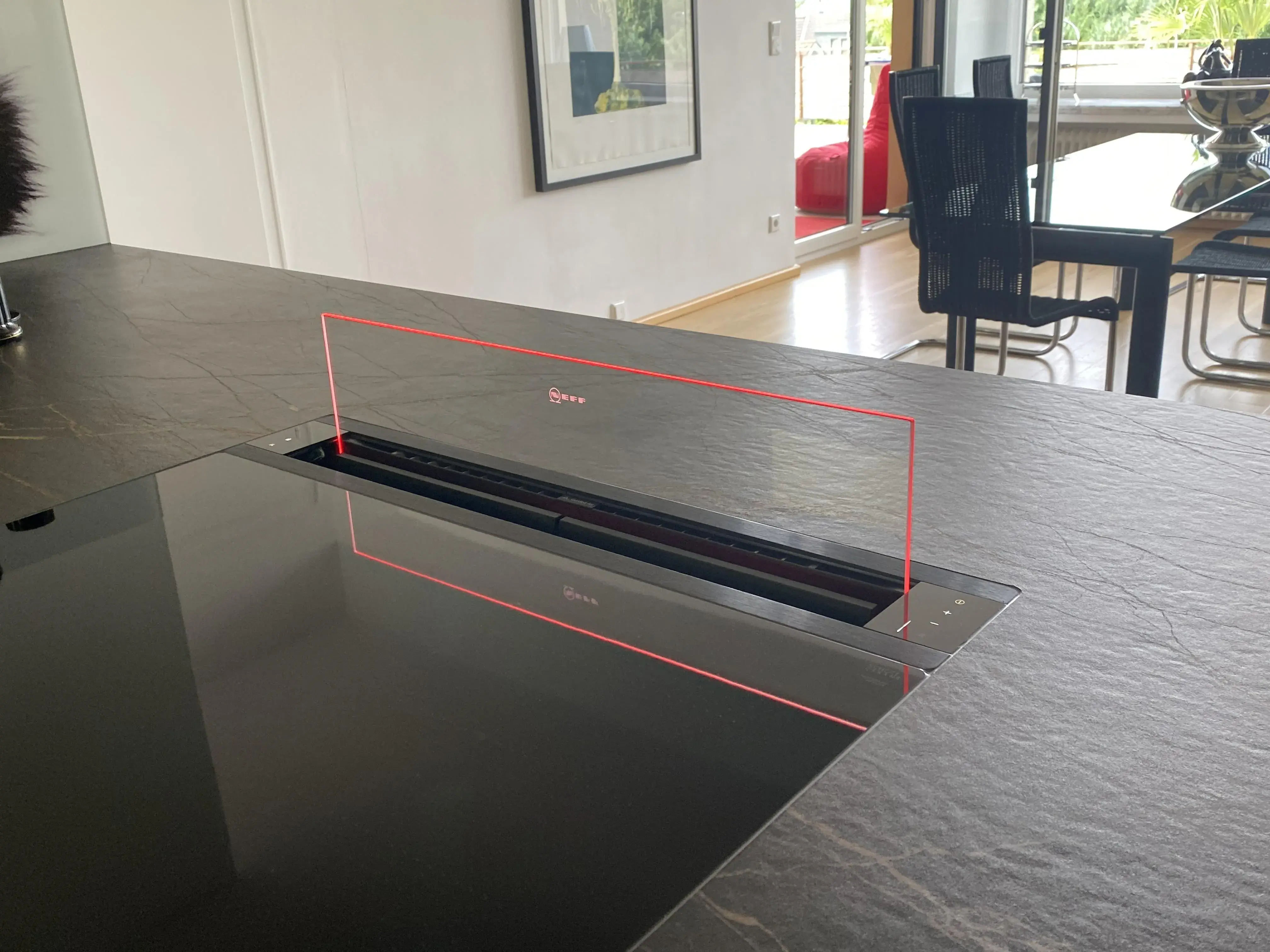 Detailblick auf eine hochgefahrenen und beleuchteten Glasschirm einer Downdraft Abzugshaube