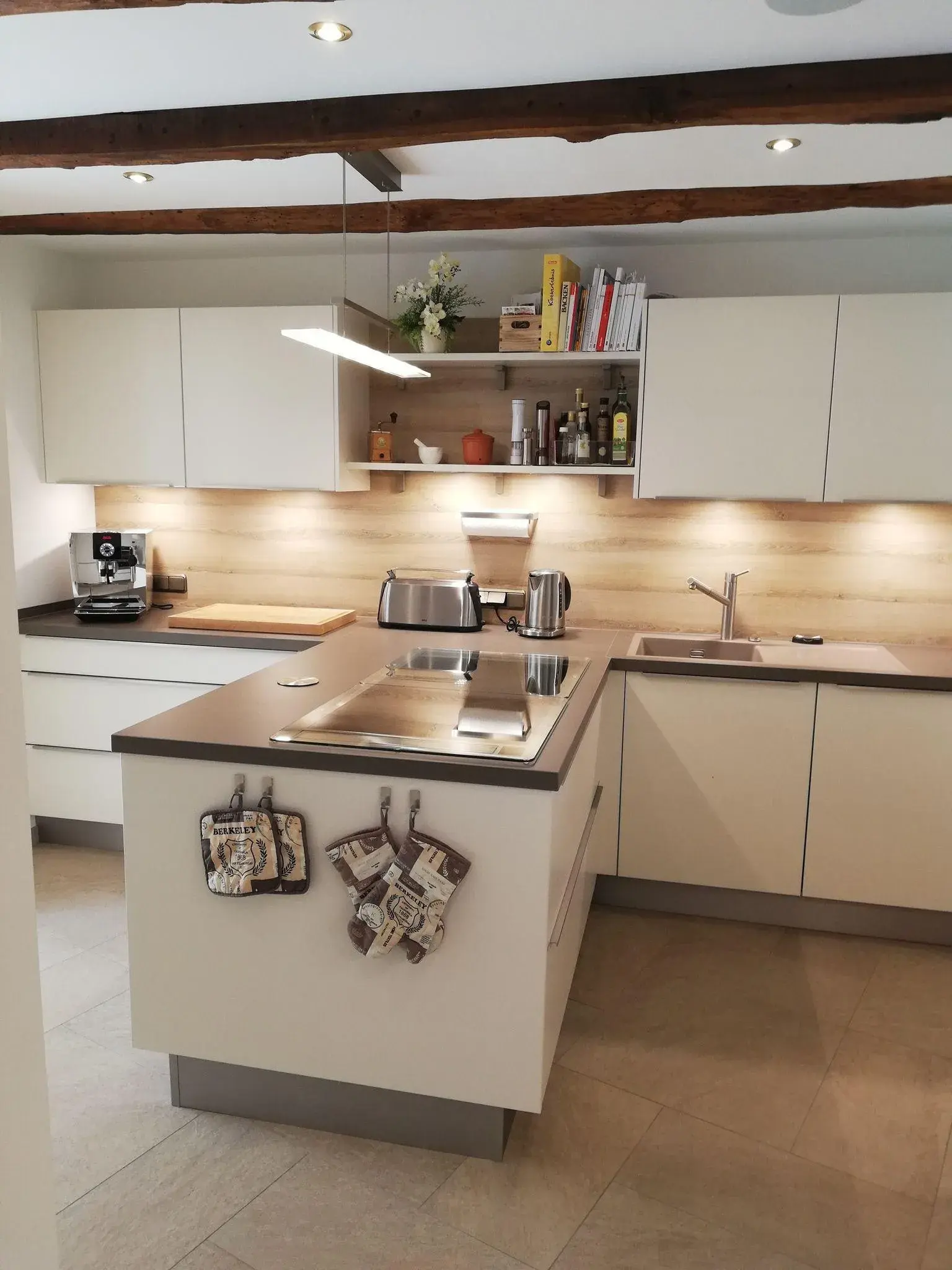 Helle, T-förmige Küche mit Regalen und beleuchteter Rückwand