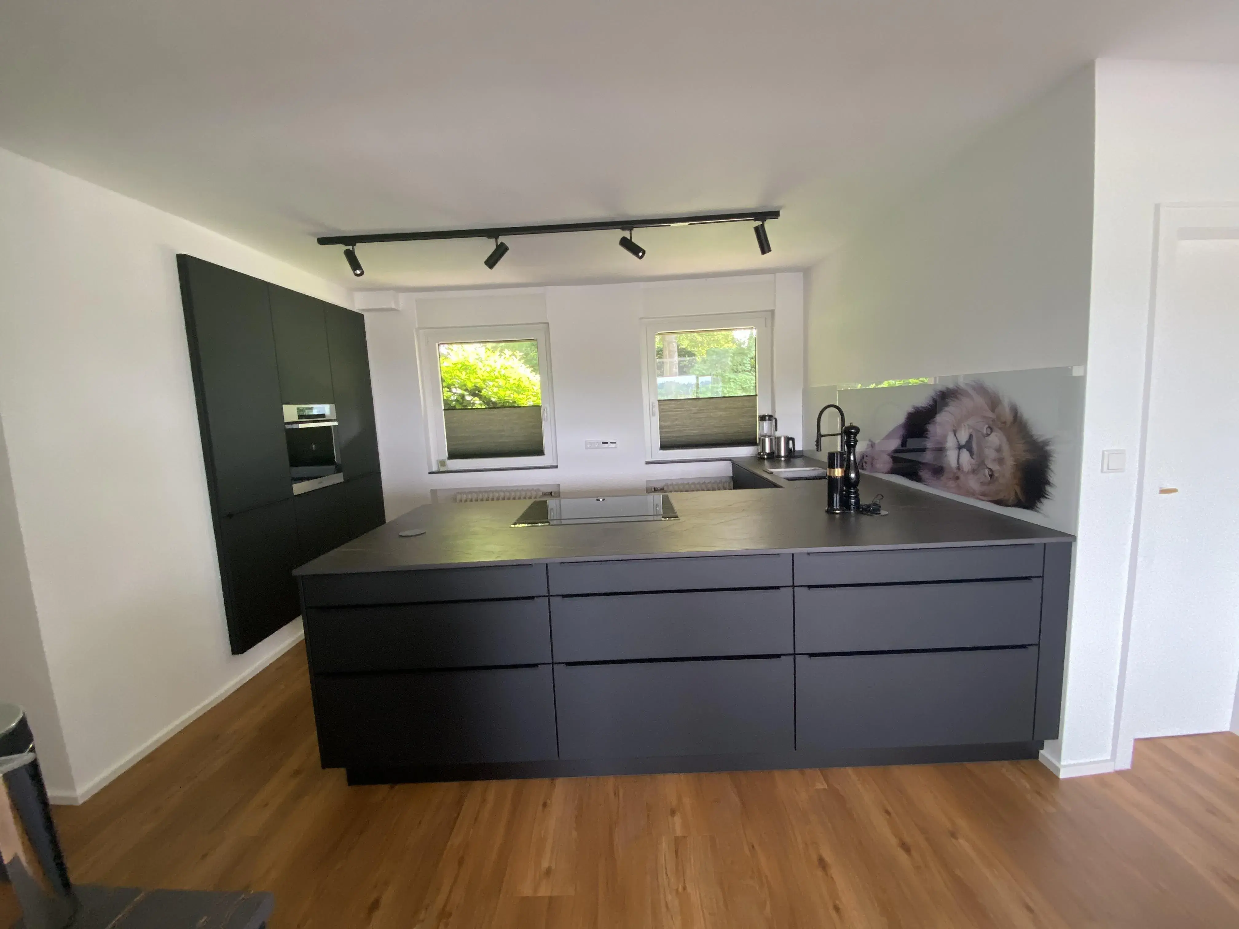 Schwarze Küche mit einer Kücheninsel und eingekofferten Hochschränken